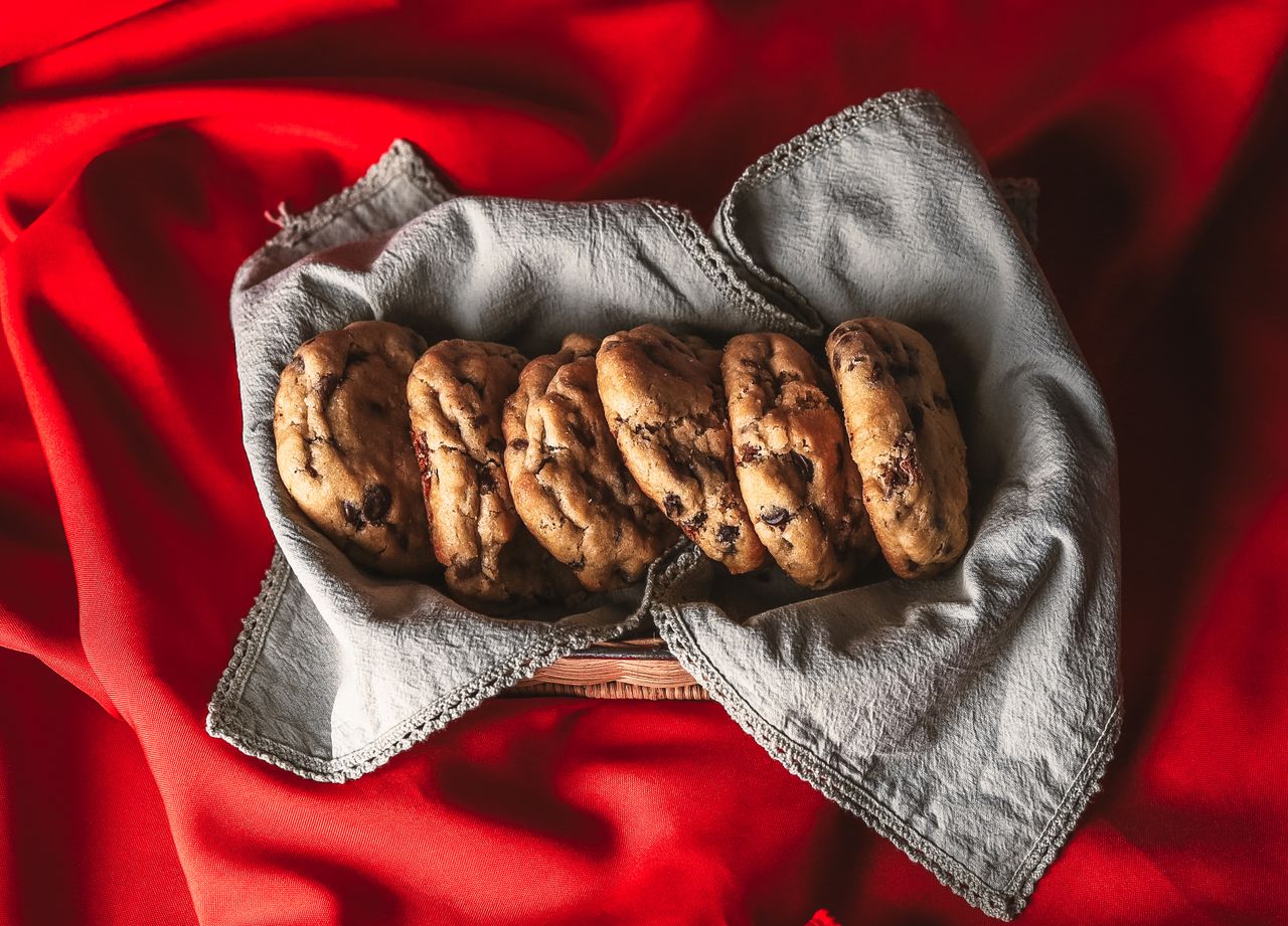services-03 A batch of delicious chocolate chip cookies resting on a cloth with a vibrant red background.