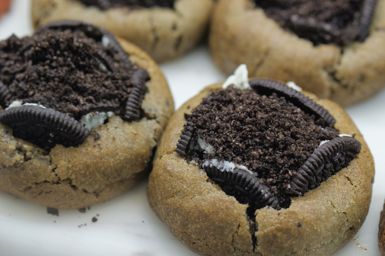 gallery-2 Close-up of baked cookies topped with Oreo crumble, a sweet and enticing treat.